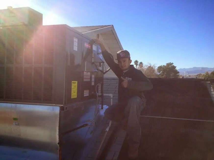 HVAC technician performing AC Tune-Up on a rooftop unit in Webster
